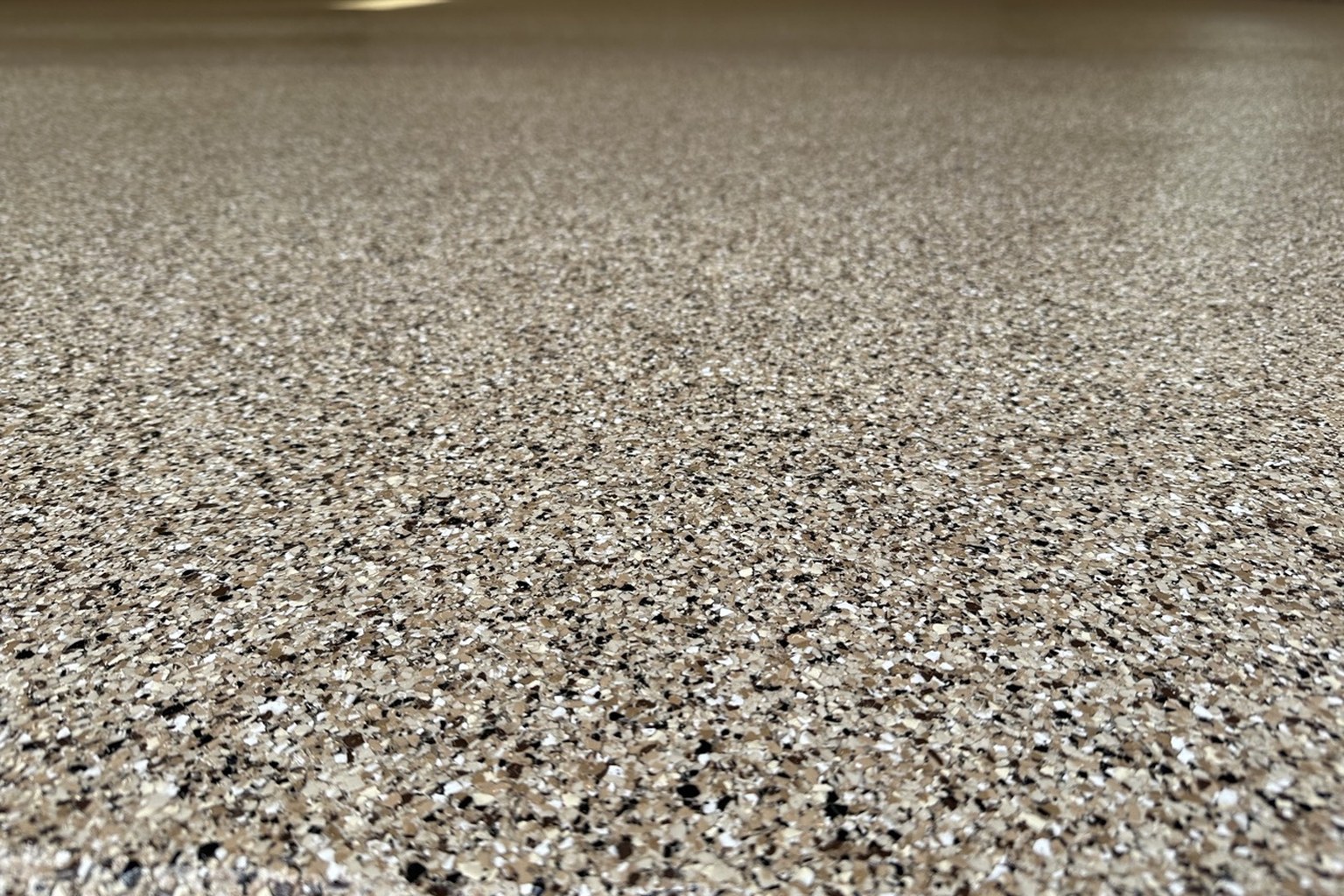 Close-up of an actual fully broadcast decorative flake floor in tan, white, gray and black.